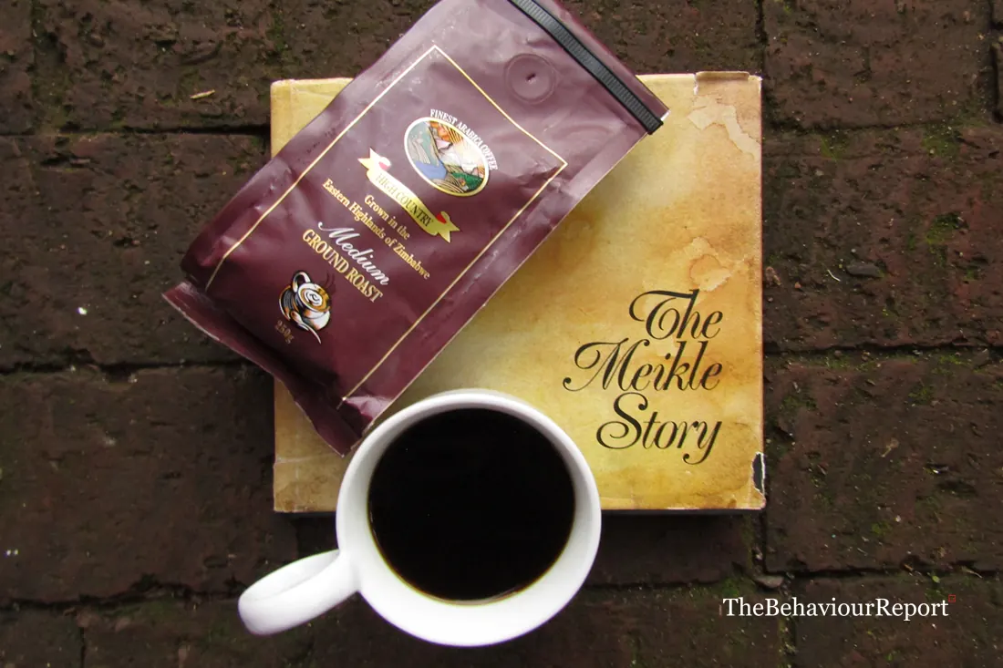 A coffee cup and a copy of The Meikles Story on a brick floor - a BehaviourReport feature.